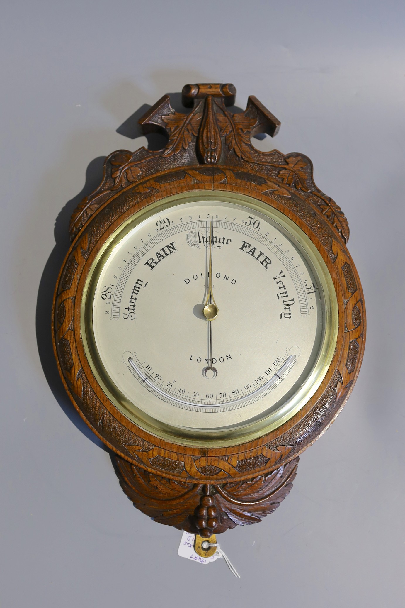 A late Victorian carved oak cased aneroid barometer and thermometer by Dollond, London, numbered 5491, height 40cm